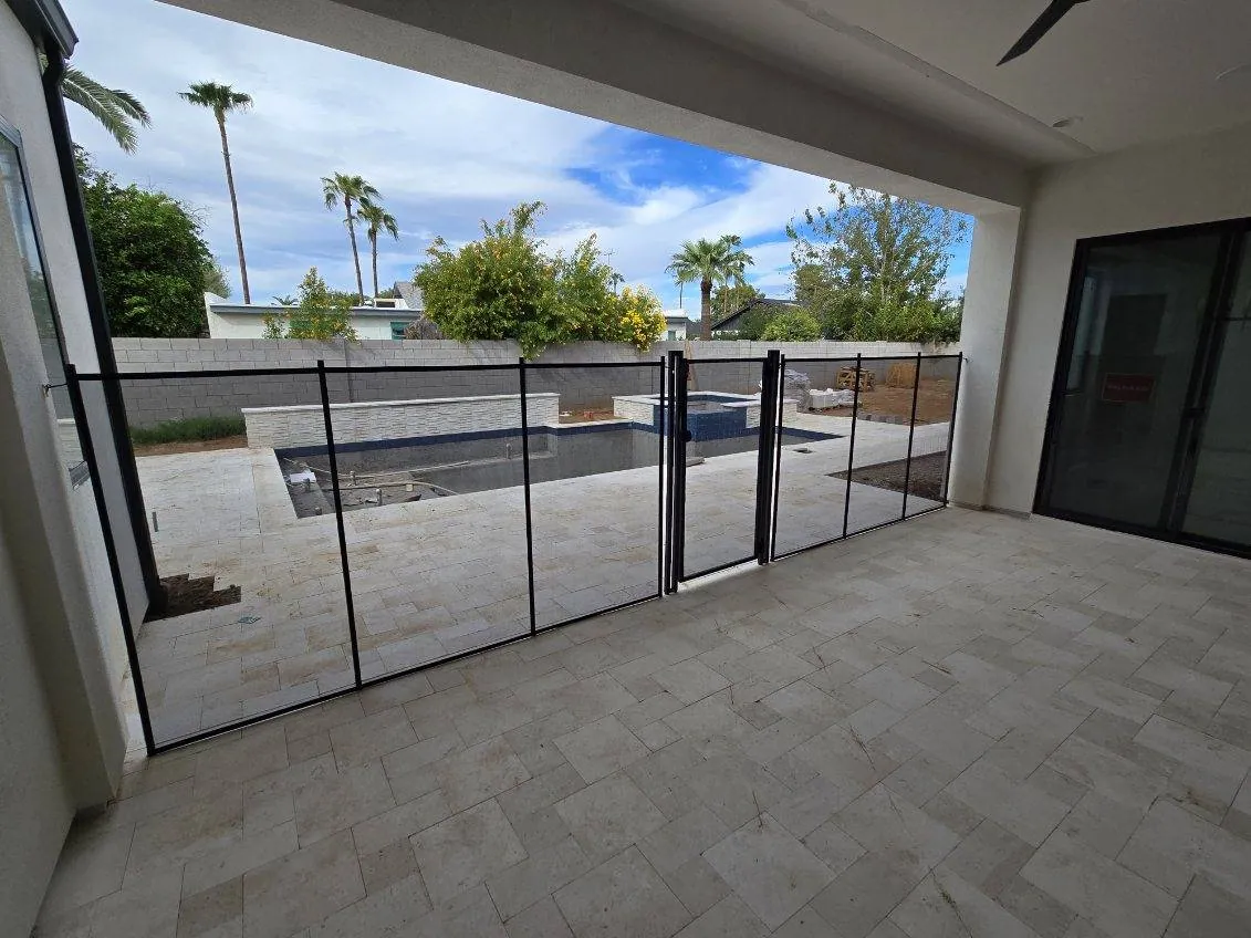 Pool gate separating a house-side patio from the water