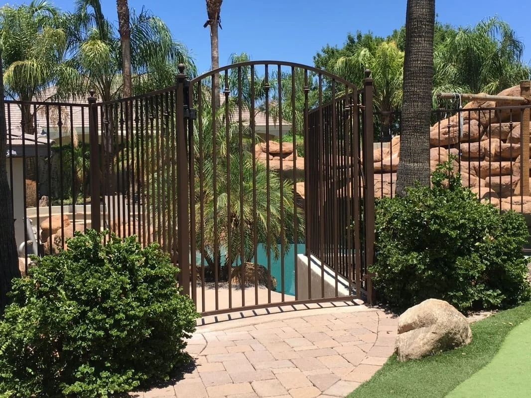 Iron pool gate set beside an Arizona stone waterfall and planting
