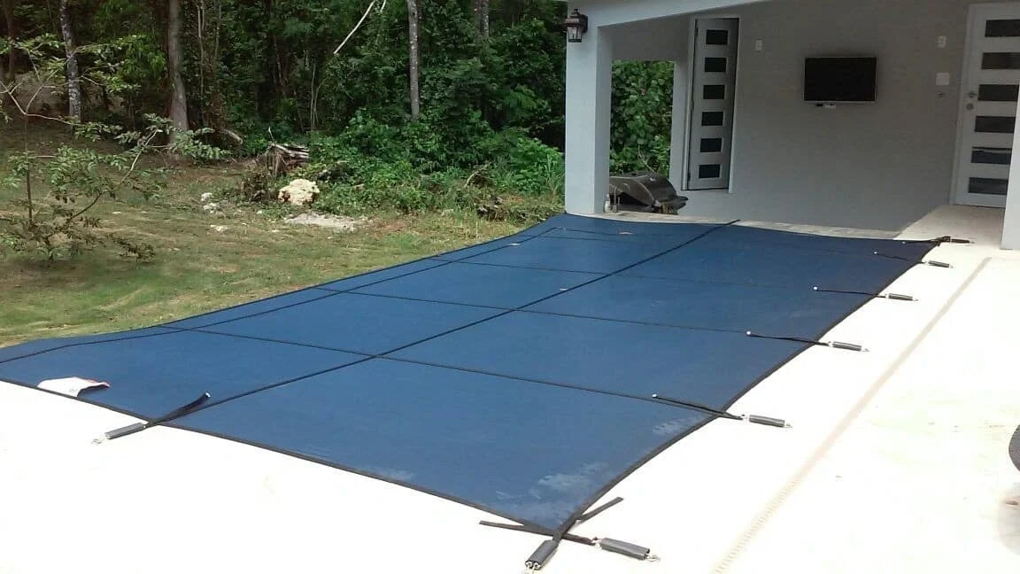 Pool cover over the water surface beside a residential pool deck